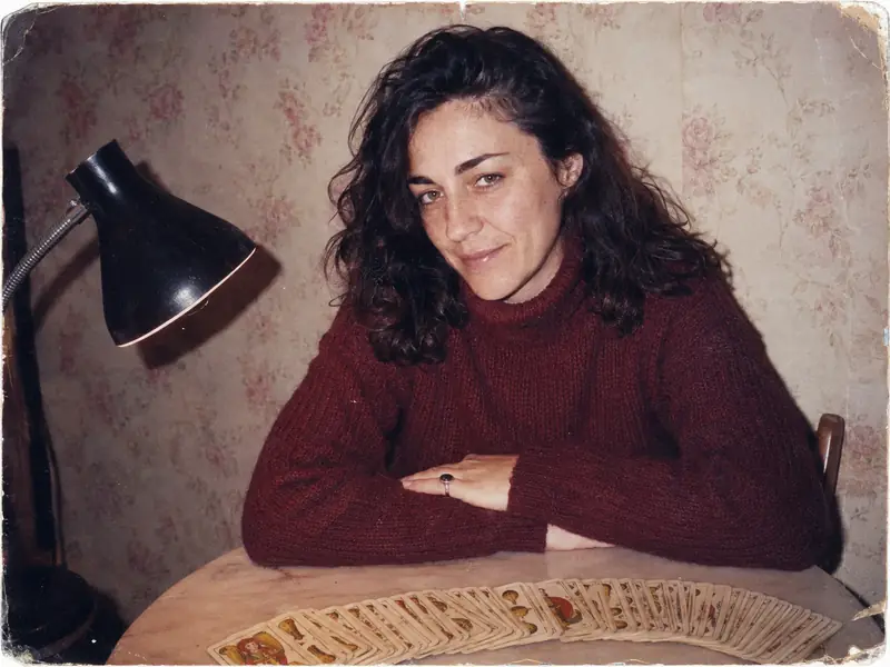 Fotografía de los años noventa de Marta Tezanos con veintitrés años ante una baraja española extendida